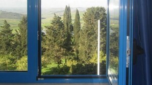 A room with a large window offering a view of a green landscape with trees and hills. - Agriturismo Campo Allegro (Santa Ninfa)