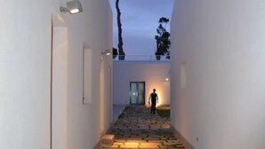 A narrow, stone-paved corridor with white walls and a door at the end. - Agriturismo Campo Allegro (Santa Ninfa)