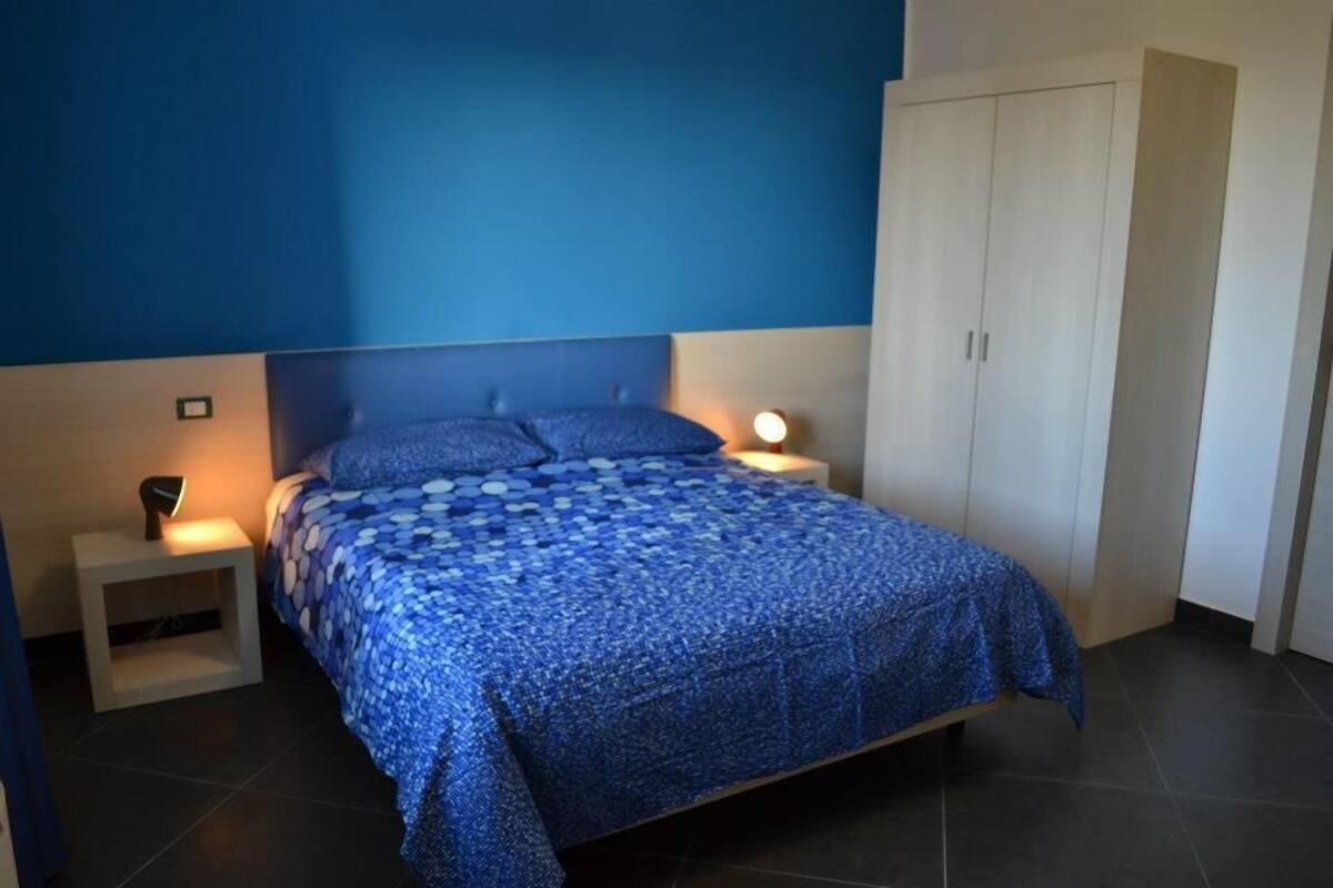 Een slaapkamer met een bed, nachtlampjes, een kledingkast en een nachtkastje.