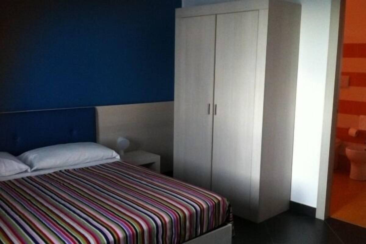 Een slaapkamer met een bed, nachtkastje en een kledingkast.