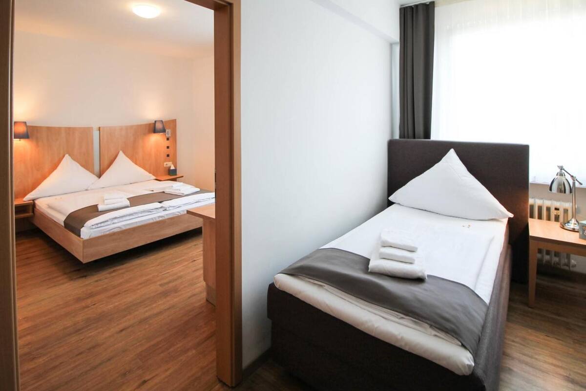 A hotel room with a large bed, a smaller bed, a desk, and a chair.