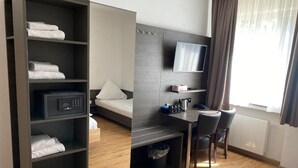 A compact hotel room with a bed, a desk with a chair, a TV, and a wardrobe. - Center Hotel Essen (Essen)