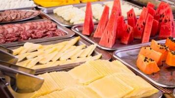 A buffet with various food options including meats, cheeses, and fruits.