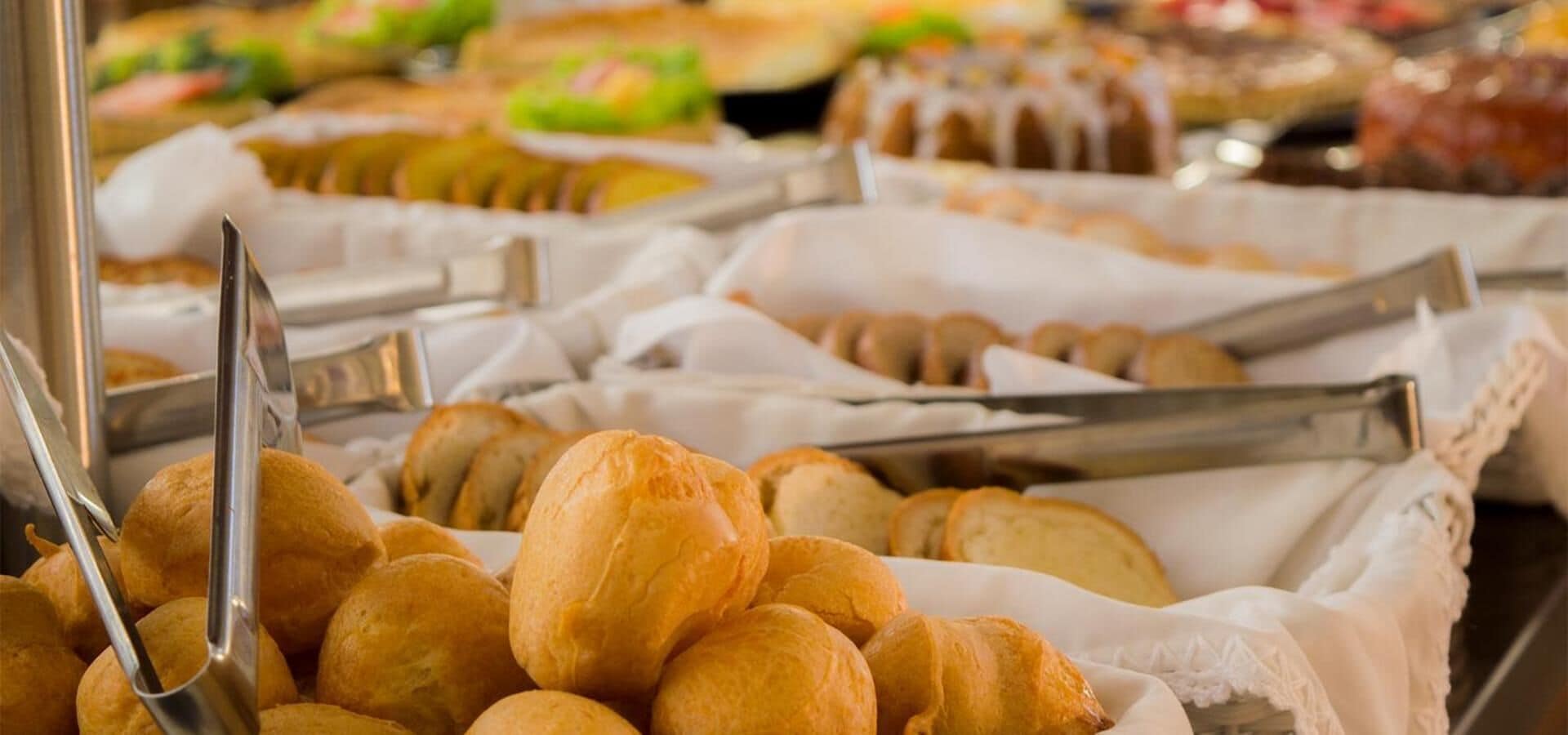 A buffet with various baked goods, including bread rolls and pastries, arranged on trays.