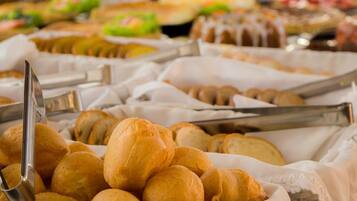 A buffet with various baked goods, including bread rolls and pastries, arranged on trays.
