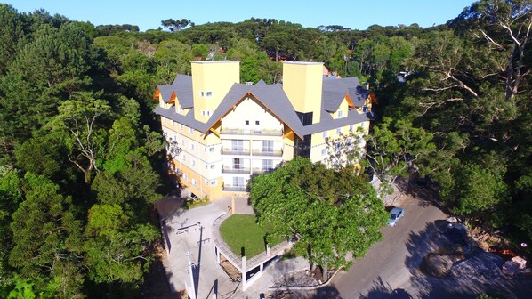 Hotel de diversos pisos amb un pati central, envoltat per un bosc dens.