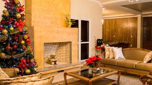A living room with a fireplace, a Christmas tree, and a sofa with cushions. - Sky Serra Hotel (Gramado)