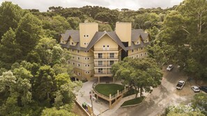 Un hotel de diversos pisos amb un pati central, envoltat per un bosc dens.