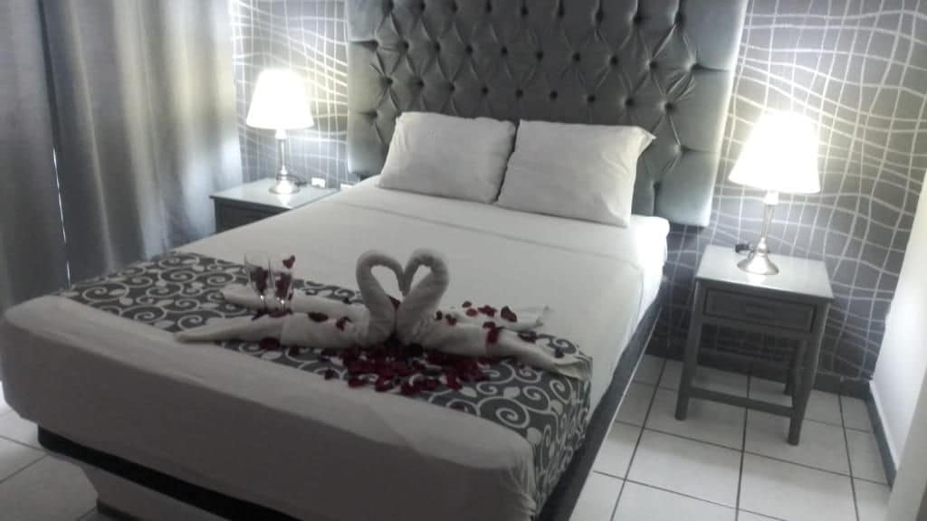 A hotel room with a large bed, two bedside tables with lamps, and a tufted headboard.