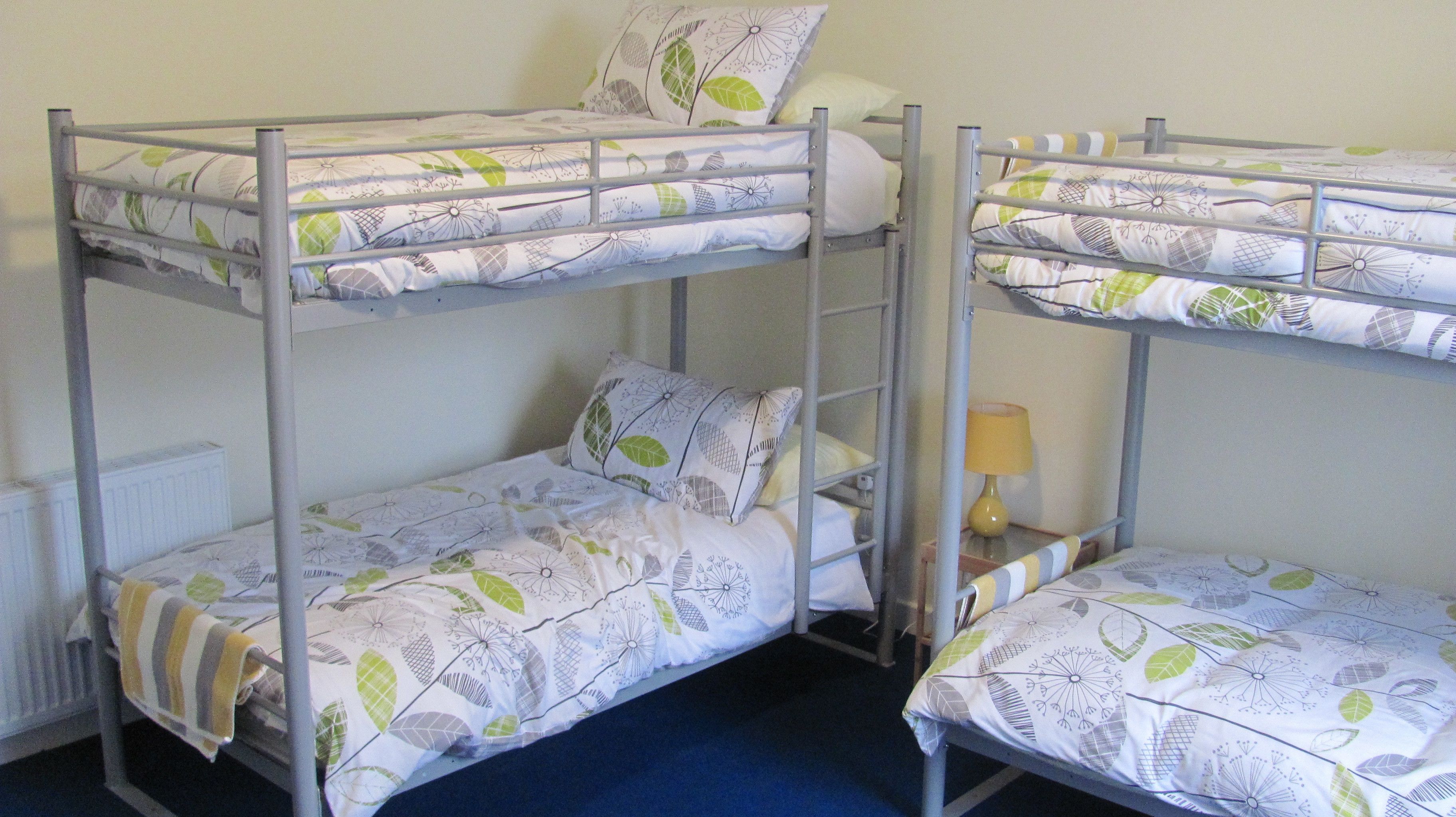 A bunk bed room with two beds, each with a patterned bedspread and pillows.