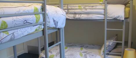 A bunk bed with a floral-patterned bedding and a bedside lamp.