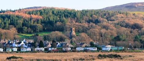 A rural village with traditional houses, a church, and a hill with trees.