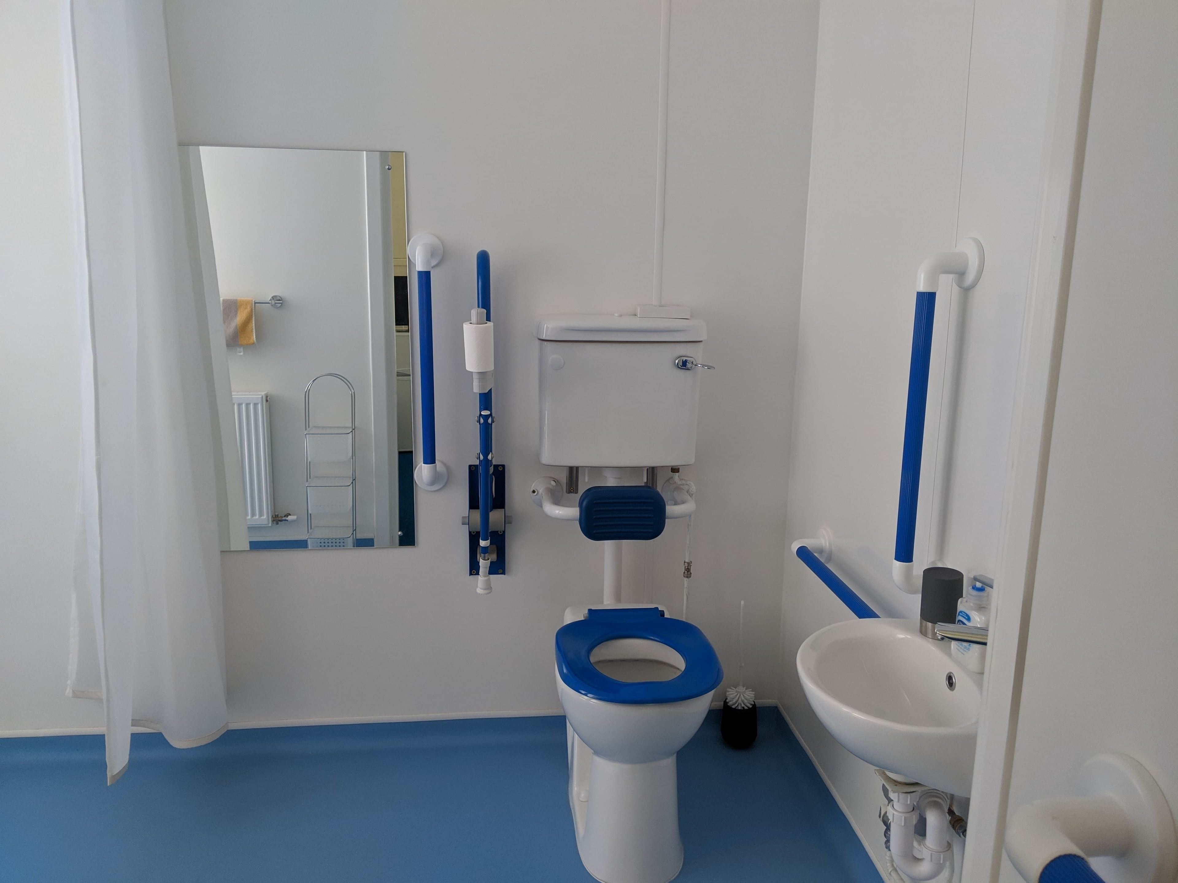 A bathroom with a toilet, sink, and mirror.