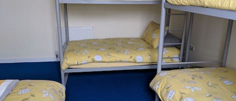 A bunk bed room with two beds, each with yellow bedding featuring leaf patterns.