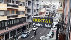 Une vue d’une rue avec une grande enseigne indiquant « HOSTAL Padre Isla » et une autre enseigne indiquant « RUTINO ».