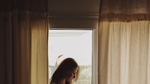 A person standing by a window with curtains, reading a book. - La Vida Otel (Urla)