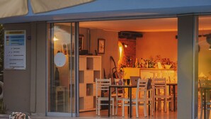 A restaurant with outdoor seating, a glass door entrance, and a balcony with a railing. - La Vida Otel (Urla)