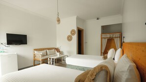 A hotel room with two beds, a TV, a small table, and a wicker chair. - La Vida Otel (Urla)