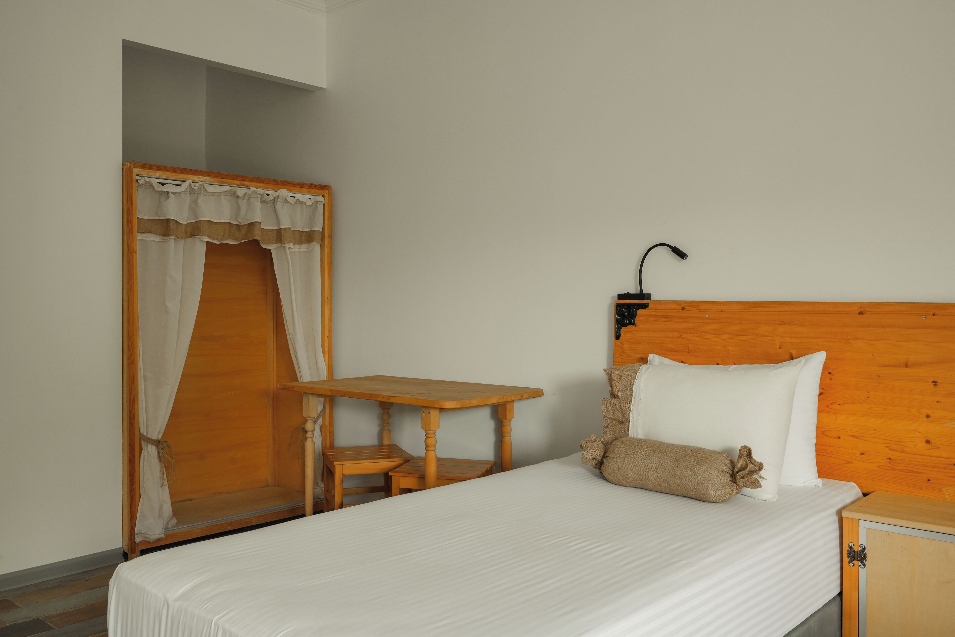 Une pièce comprenant un lit, une table de chevet en bois, une petite table et une armoire en bois.