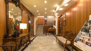 Un hall d’hôtel doté d’un magnifique escalier, d’un comptoir d’accueil et d’un espace salon.