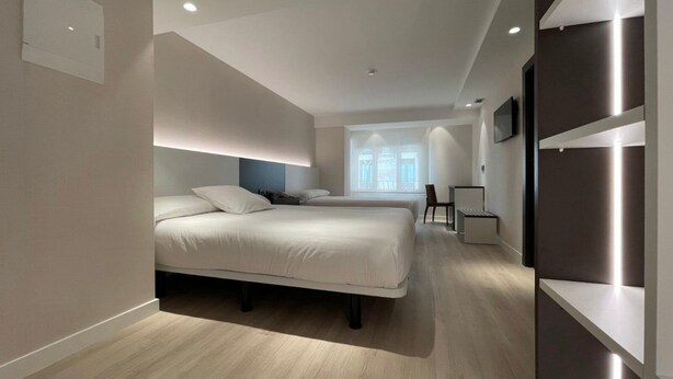 Une chambre d’hôtel moderne avec deux lits, un bureau et une grande fenêtre.