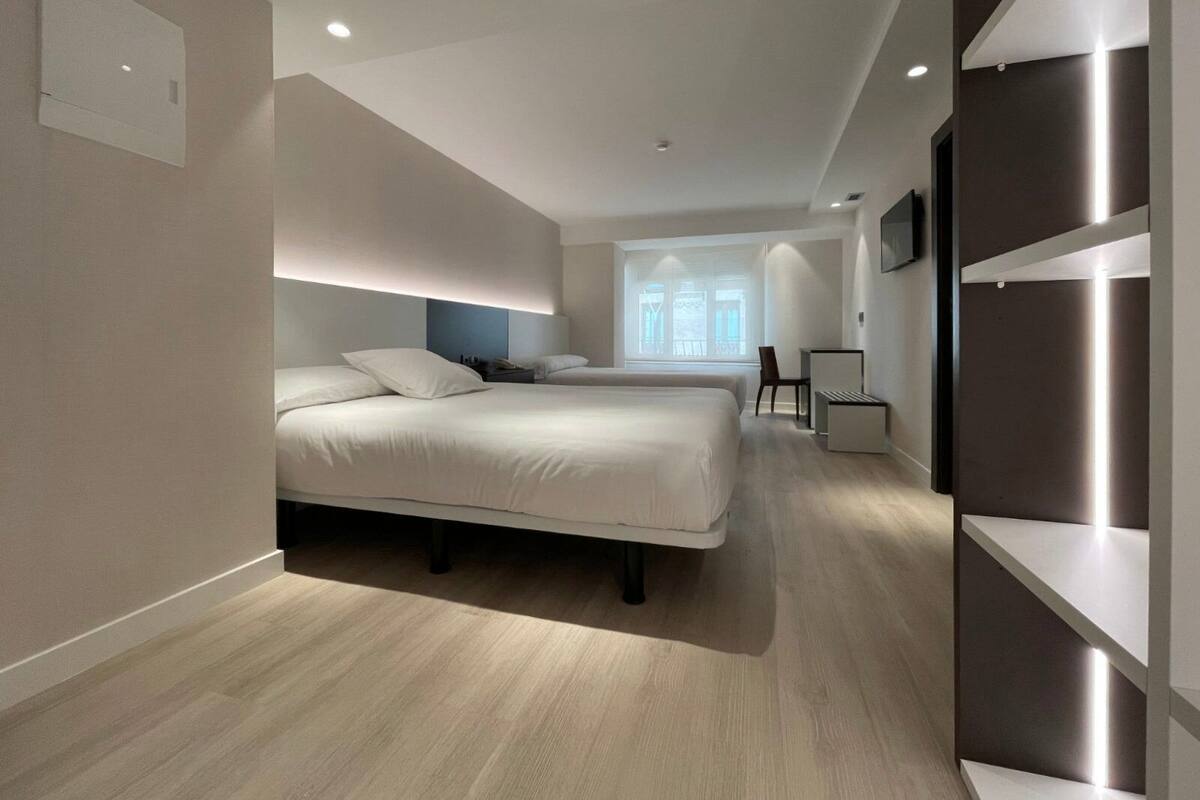 Una habitación de hotel moderna con dos camas, un escritorio y un ventanal grande.