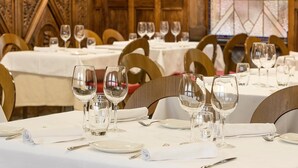 Un espace repas avec des tables dressées pour le service, agrémenté de nappes blanches et de chaises en bois.