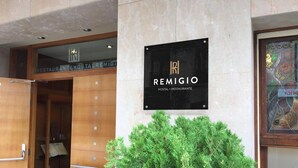 Une enseigne pour l’auberge et le restaurant Remiglio, avec une entrée en bois et un grand buisson vert devant.