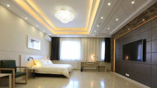 Une chambre d’hôtel moderne avec un grand lit, un bureau, un téléviseur fixé au mur et un lustre.
