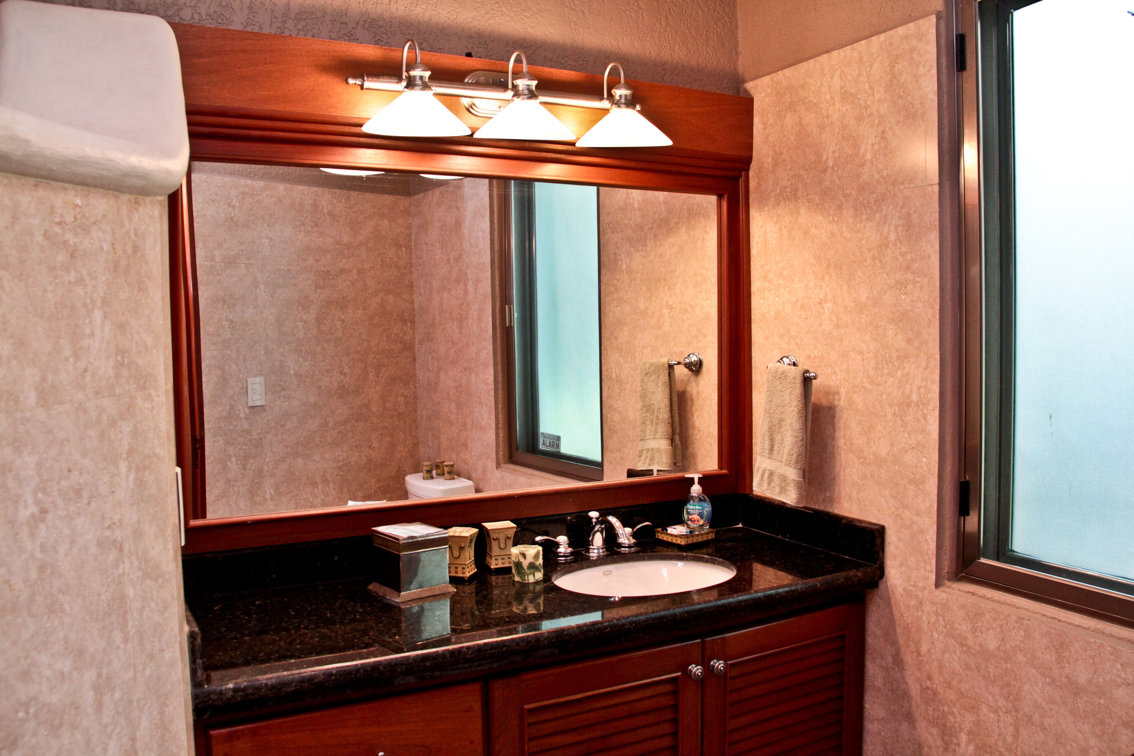 A bathroom with a large mirror, a sink, and a window.