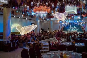 Un comedor amplio con mesas dispuestas para invitados, una araña y detalles decorativos.