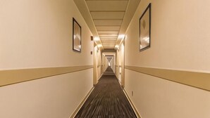 Un largo y estrecho pasillo de hotel con suelo de moqueta y cuadros enmarcados en las paredes.
