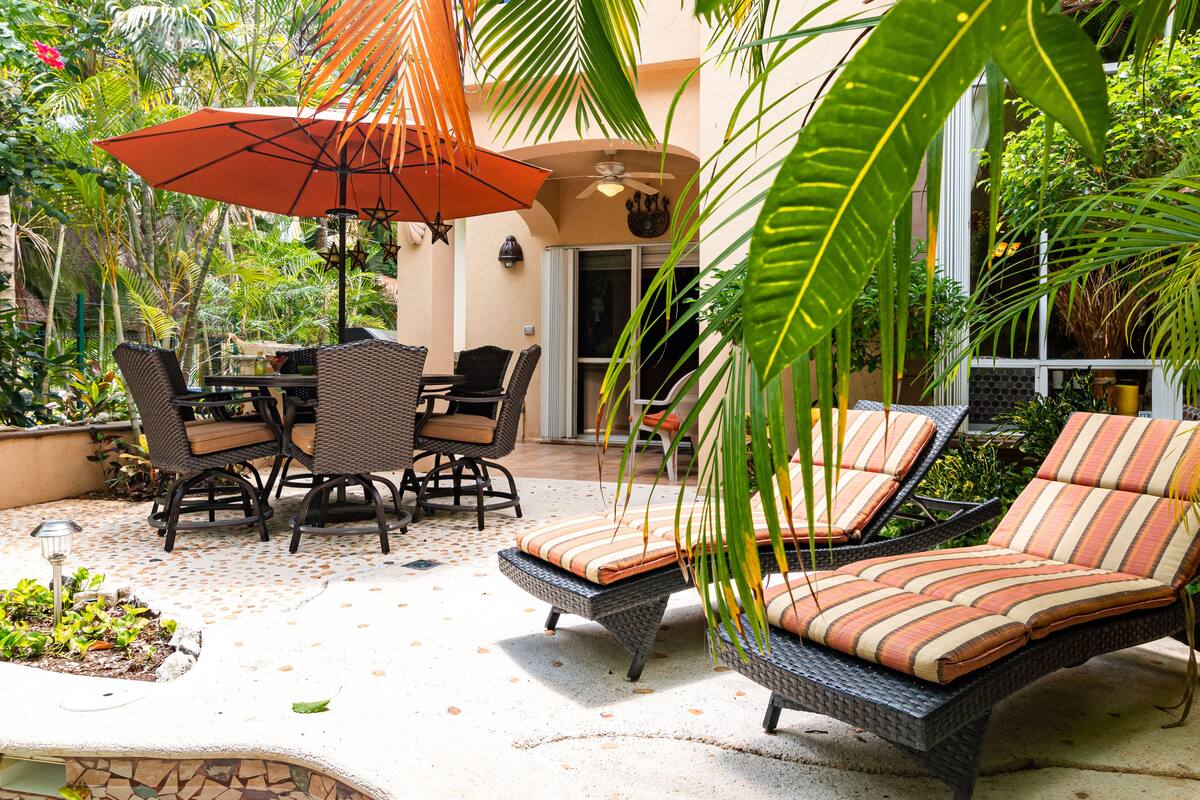 Eine Terrasse im Freien mit Korbmöbeln, einem Tisch und gestreiften Kissen.