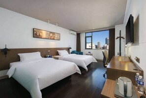 A hotel room with two beds, a desk, a coffee maker, a water bottle, and a city view. - Microtel by Wyndham Kunming City Center (Kunming)