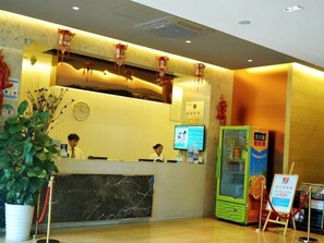 A hotel reception area with a marble counter, a reception desk, a digital screen, a vending machine, and a potted plant. - Microtel by Wyndham Kunming City Center (Kunming)