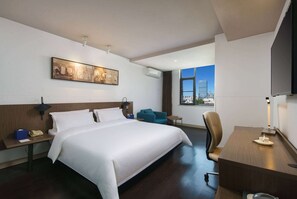 A modern hotel room with a large bed, a desk, a chair, and a television. - Microtel by Wyndham Kunming City Center (Kunming)