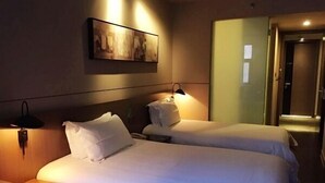A hotel room with two beds, a painting on the wall, and a door leading to another room. - Jinjiang Inn Select Shanghai Chuansha Subway Station (Shanghai)