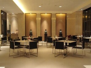 A hotel dining area with multiple tables and chairs, large windows, and decorative vases. - Jinjiang Inn Select Shanghai Chuansha Subway Station (Shanghai)