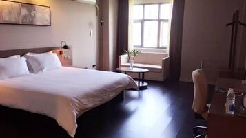 Relax in comfort with a large bed, a small table, and a chair, set against a window with a view.