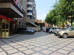 A street with parked cars and a building with a sign in a foreign language. - Jinjiang Inn Benxi Coach Statio (Benxi)