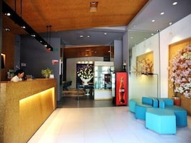 Área de recepção de hotel com balcão, espaço de estar e uma parede decorativa.