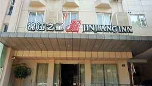 Hotellin sisäänkäynti, jossa on kyltti, jossa lukee ”JINJIANGINN”, ja sen yläpuolella hotellin logo.