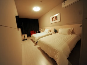 A hotel room with two beds, a desk, a chair, a nightstand, and a ceiling light. - Jinjiang Inn (Xinchang Gushan Road Giant Buddhist Temple) (Shaoxing)