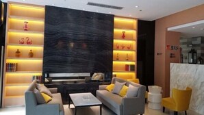 Eine moderne Hotelhalle mit einer Sofagruppe, einem Couchtisch und einer Rezeption.