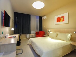 A hotel room with a bed, a desk, a chair, a small table, and a window with curtains. - Jinjiang Inn Daqing Lande Lake (Daqing)