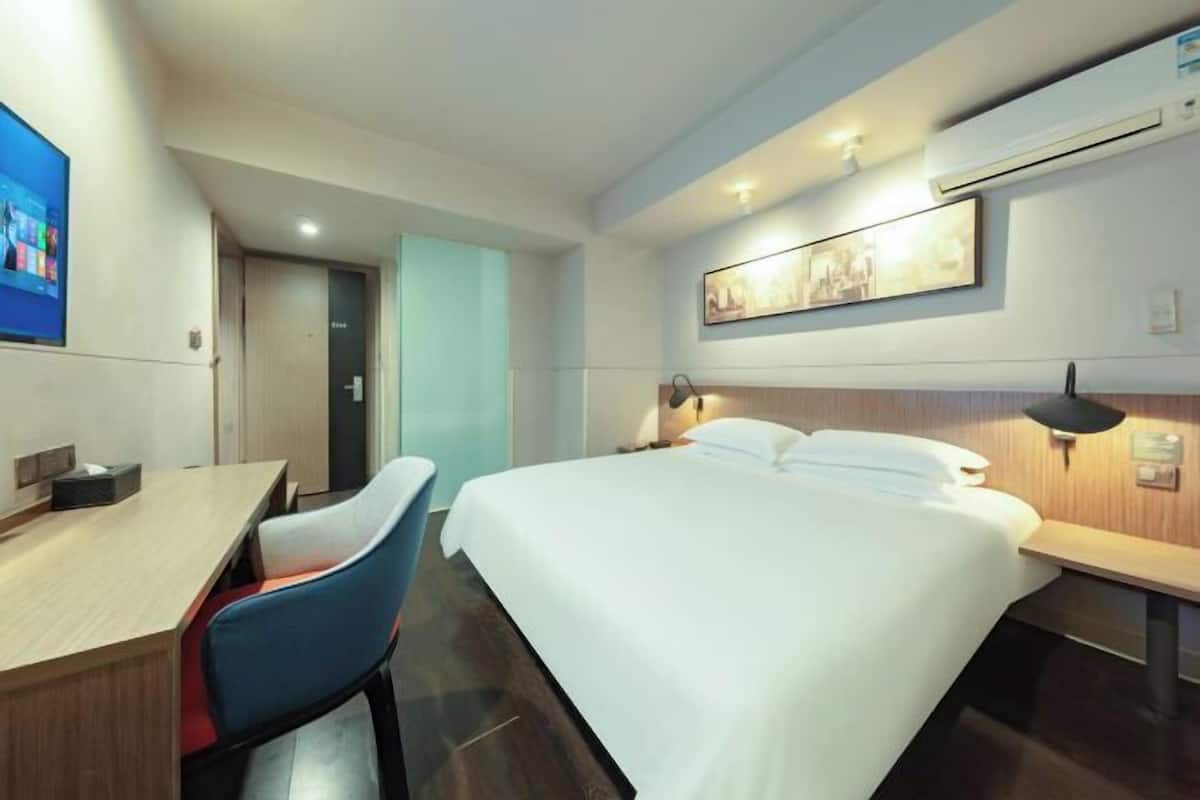 A hotel room with a bed, a desk, and a chair.