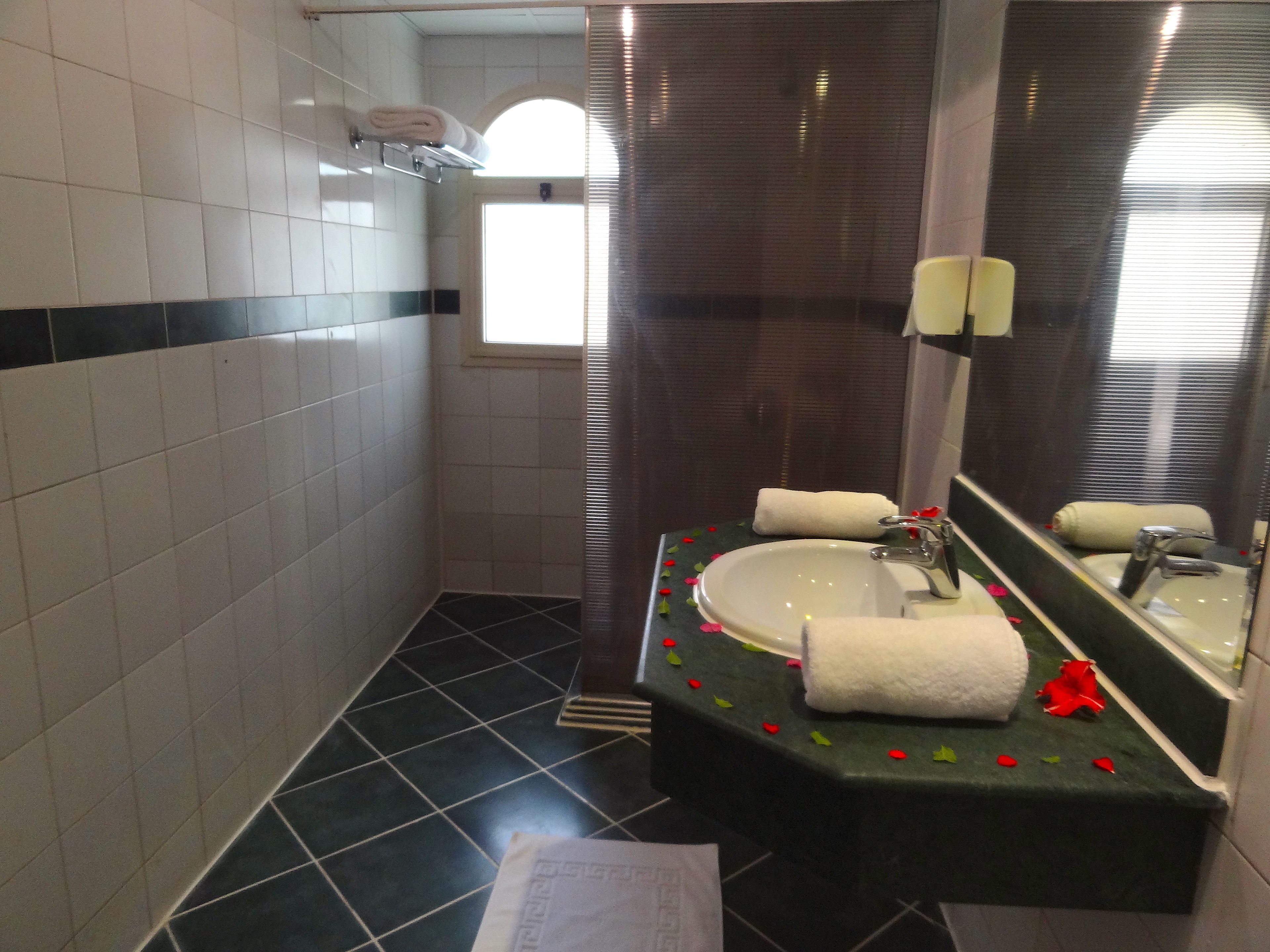 A bathroom with a white sink, a mirror, and a window.