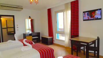 Une chambre d’hôtel avec deux lits, un bureau, une chaise, une télévision et une fenêtre avec des rideaux.