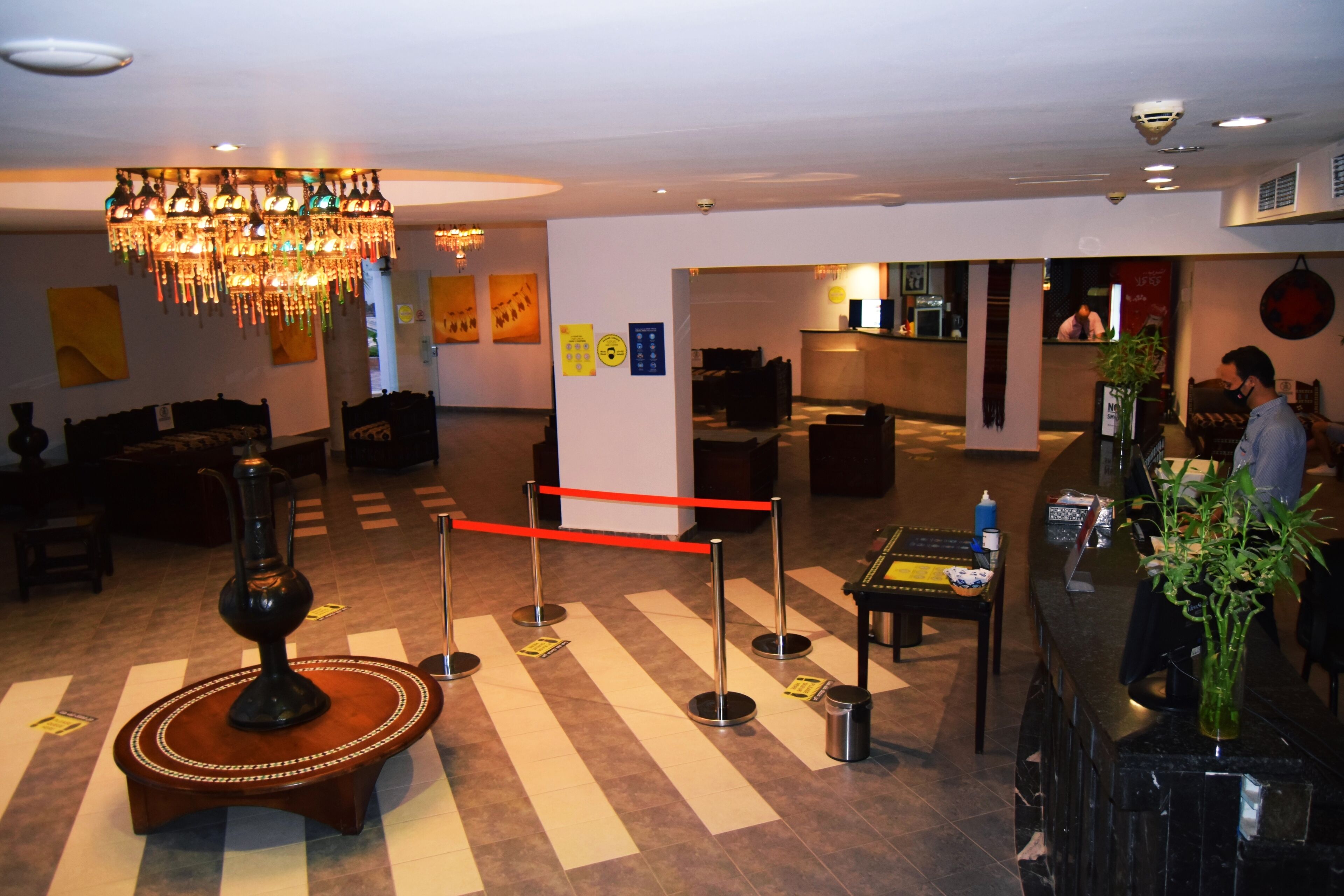 Un hall d’entrée agrémenté d’un lustre, d’un comptoir de réception et d’un espace détente doté d’un sol à motifs.