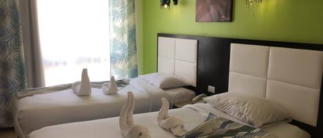 A hotel room with two beds, a green wall, and a painting.
